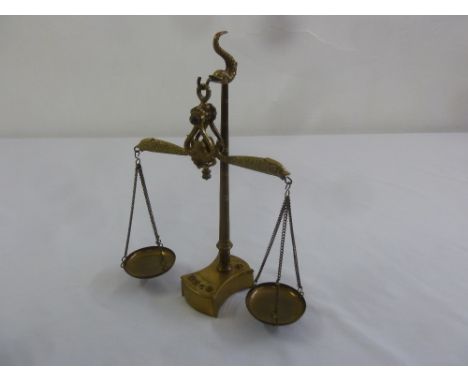 A brass balance scale of customary form to include weights (one weight missing)