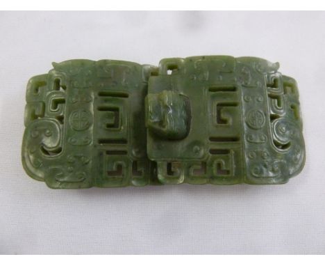 A Chinese green jade carved and pierced two part belt buckle with stylised mask clasp