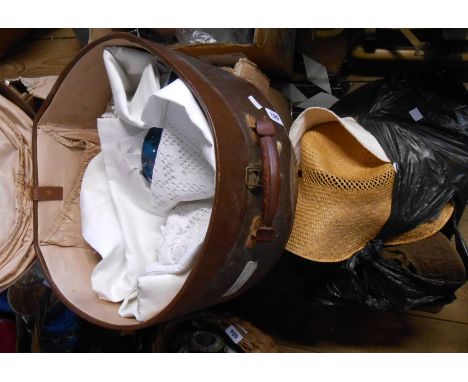 An old hatbox containing a quantity of textiles including embroidered and crochet tablecloths - sold with a bag of straw hats