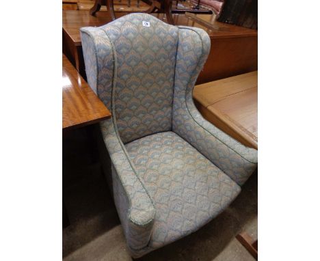 A late Victorian wing back armchair with piped machine tapestry upholstery, set on turned front legs with brown porcelain cas
