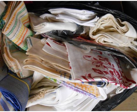 A bag containing a large quantity of assorted textiles including damask and other tablecloths, crochet cloths, etc.