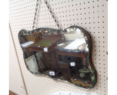 A vintage frameless wall mirror with shaped and faceted plate