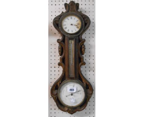 A late Victorian carved oak cased combined wall barometer and timepiece with eight day movement, aneroid works, spirit temper