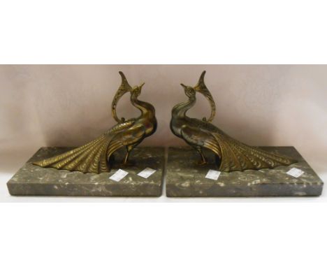 A pair of Art Deco cast brass peacock form bookends on marble plinths