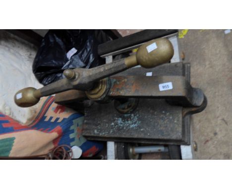 A large antique cast iron book press with brass acorn finial, large brass handle grips and remains of original black japanned