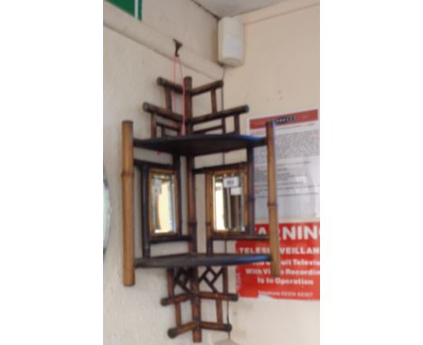 A Victorian bamboo corner shelf with two bevelled mirror plates and curved surfaces