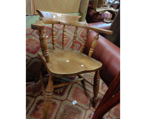 An antique smoker's bow elbow chair with solid moulded elm seat, set on ring turned supports