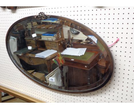 A vintage coppered metal framed bevelled oval wall mirror with applied decoration