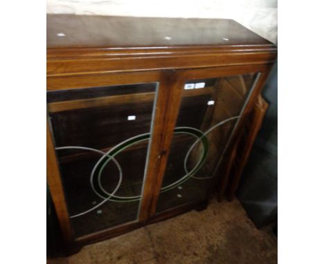 A 92cm polished oak display cabinet with glass shelves enclosed by a pair of Art Deco leaded glazed panel doors, set on brack