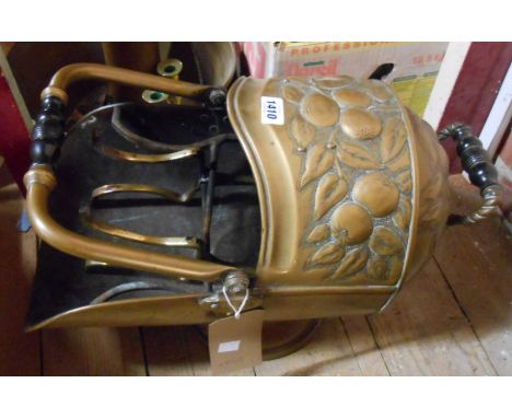 An Arts and Crafts Movement helmet form coal scuttle with repousse work apple decoration and ebonised handles - sold with two