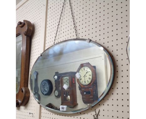 A vintage frameless bevelled oval wall mirror with chrome plated plate clips