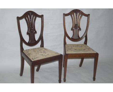 A pair of Edwardian Hepplewhite style mahogany dining chairs, with pierced shield backs, drop in tapestry seats, raised on st