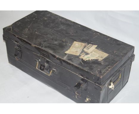 An early 20thC tin trunk, painted in black, bearing labels, 33cm high, 83cm wide, 40cm deep.