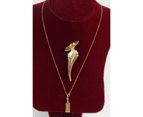 A 9ct ingot, upon a fine 9ct gold curb chain together with 9ct gold brooch cast as an Art Deco lady, total weight 7.9g.