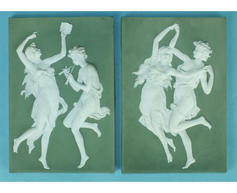 A pair of early-20th century Continental moulded ceramic plaques, decorated white on green with dancing female figures and mu