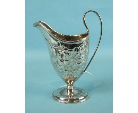 A Georgian large helmet-shaped cream jug with overall embossed foliate decoration, raised on a circular base, 16cm high, mark