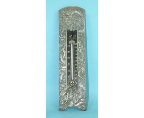 An early-20th century Chinese thermometer within a white metal frame embossed with dragons, 23cm high, 6cm wide.