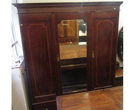 An Edwardian inlaid mahogany wardrobe with a central mirrored door flanked by a pair of blind doors above two drawers on spla