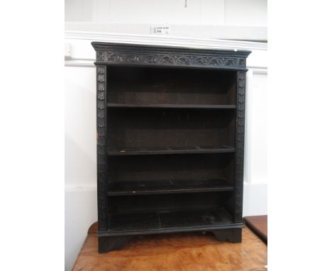 An oak carved and black stained open bookcase with four shelves on bracket feet, height 116cm, width 90cm, depth 28cm.