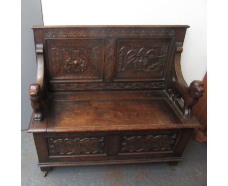 A oak hall bench, early 20th century, the back with two square panels carved each carved with an interior scene with three ge