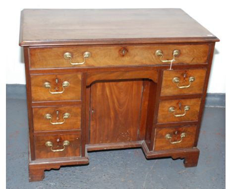 A George III mahogany kneehole desk, the single frieze drawer above a cupboard door flanked by six drawers, on bracket feet, 