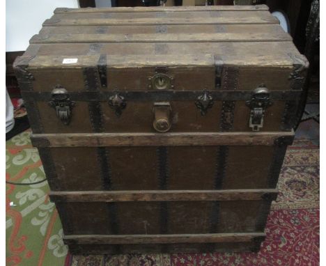 A large canvas covered and metal bound wooden trunk, with a pair of leather carrying handles, height 93cm, width 82cm, depth 