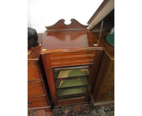 A walnut music cabinet, early 20th century, the serpentine moulded top above a glazed door enclosing five shelves on bracket 