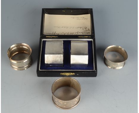 A pair of engine turned silver napkin rings cased and three other silver napkin rings. 3oz.