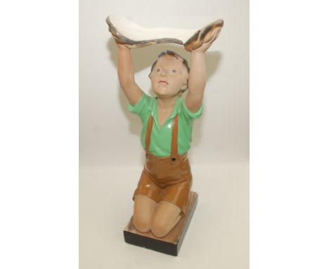 A 1930s plaster model of a kneeling boy wearing a green shirt and shorts with his arms aloft originally holding a goldfish bo