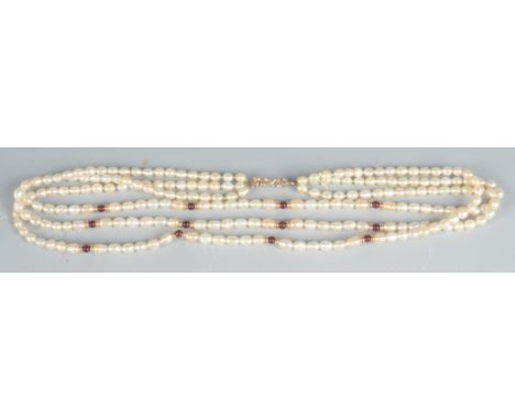 A triple strand pearl necklace spaced with garnets and gold beads. 
