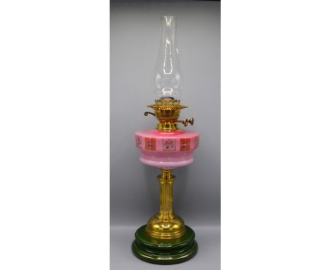 A brass and pink glass oil lamp, the reeded column on a circular plinth pottery base, total height 65cm.