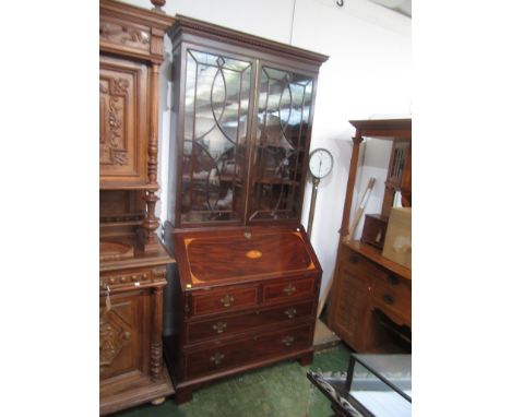 A George III style mahogany bureau bookcase, the dentil cornice above a pair of astragal glazed doors enclosing four shelves,