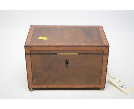 A Victorian walnut and banded tea caddy, with twin lions head and ring handle, raised on brass ball feet, 20cms wide.