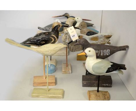 A collection of carved wood garden bird sculptures, each raised on a pillar stick support over block base, the tallest 35cms 