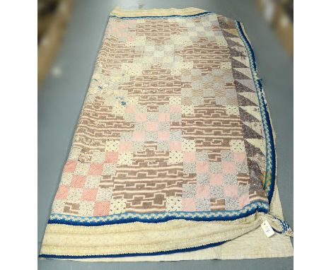 An early Victorian patchwork quilt, comprising printed square and triangular blocks arranged in a geometric design, framed by