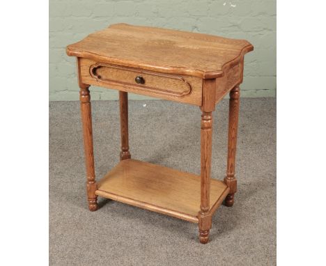 A light oak two side side table featuring singular drawer. Approx. dimensions 61cm x 39cm x 68cm.  