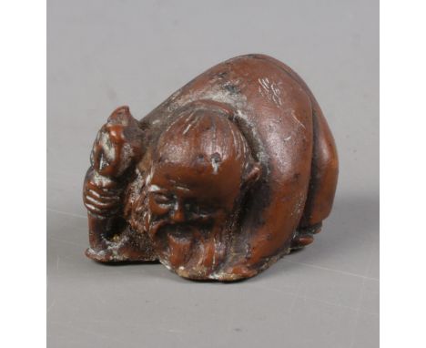 A Japanese carved hardwood netsuke formed as crouching elder holding a staff.  