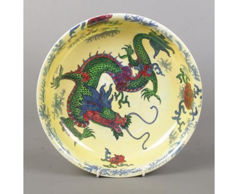 A Bursley Ware 'Dragon' ceramic bowl, decorated with central dragon motif, blue dotted rim and foliage, on a pale yellow back