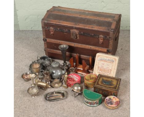 A vintage dome top trunk filled with various metalwares including silver plate, brass and tins  