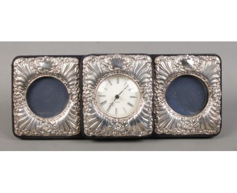 A silver mounted three section easel display stand, with central quartz clock flanked by two circular photo frames. Assayed B