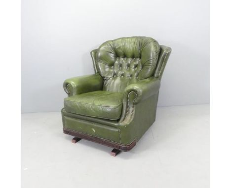 A green button back leather upholstered Chesterfield style wing back rocking chair. 