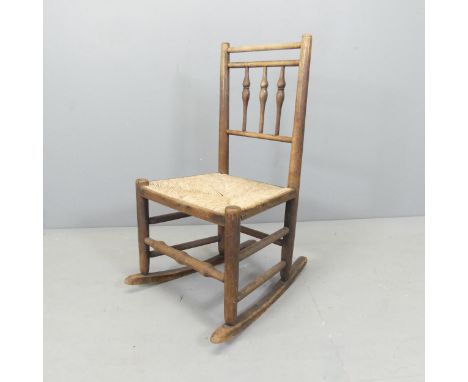 A Victorian child's oak and rush seated rocking chair, with bobbin turned back. Overall 46x83x57cm. 