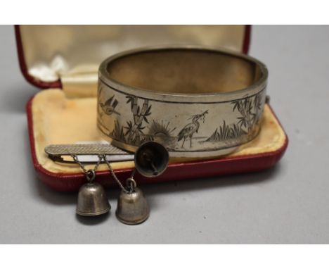 A vintage white metal etched bangle and a bar brooch having bell details, marked silver to rear.