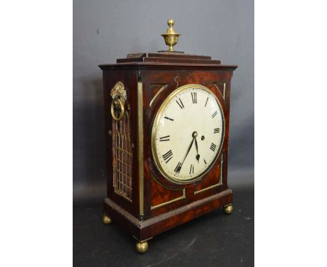 A Regency Mahogany and Brass Mounted Bracket Clock with brass finial and lion ring side handles raised upon low brass ball fe