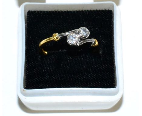 An 18 carat gold diamond cross over ring, two round brilliant cut diamonds in rubbed over settings, to bypass shoulders, tota