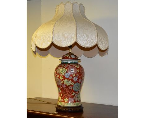 A Chinese glazed pottery vase lamp with shade, decorated with floral panels on red ground, raised on wooden stand, 40cm high