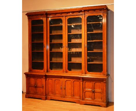 A large Victorian oak library bookcase, the moulded cornice with carved motifs above glazed doors, flanked by a further glaze