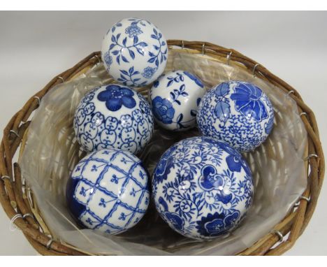 6 blue and white ceramic balls in a wicker basket.