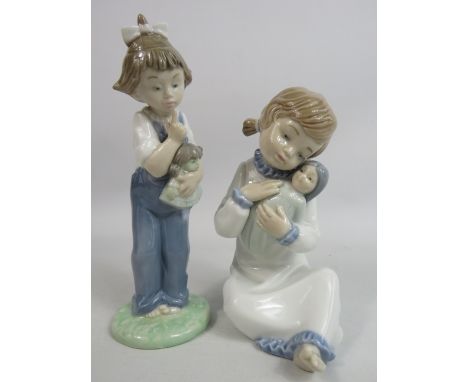2 Nao figurines of Little girls holding dolls.