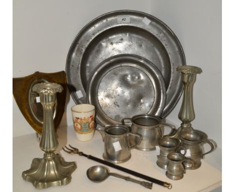 A velvet framed shield shaped mirror; a pair of silver plated candlesticks; a pewter charger, pewter gill measures, toasting 
